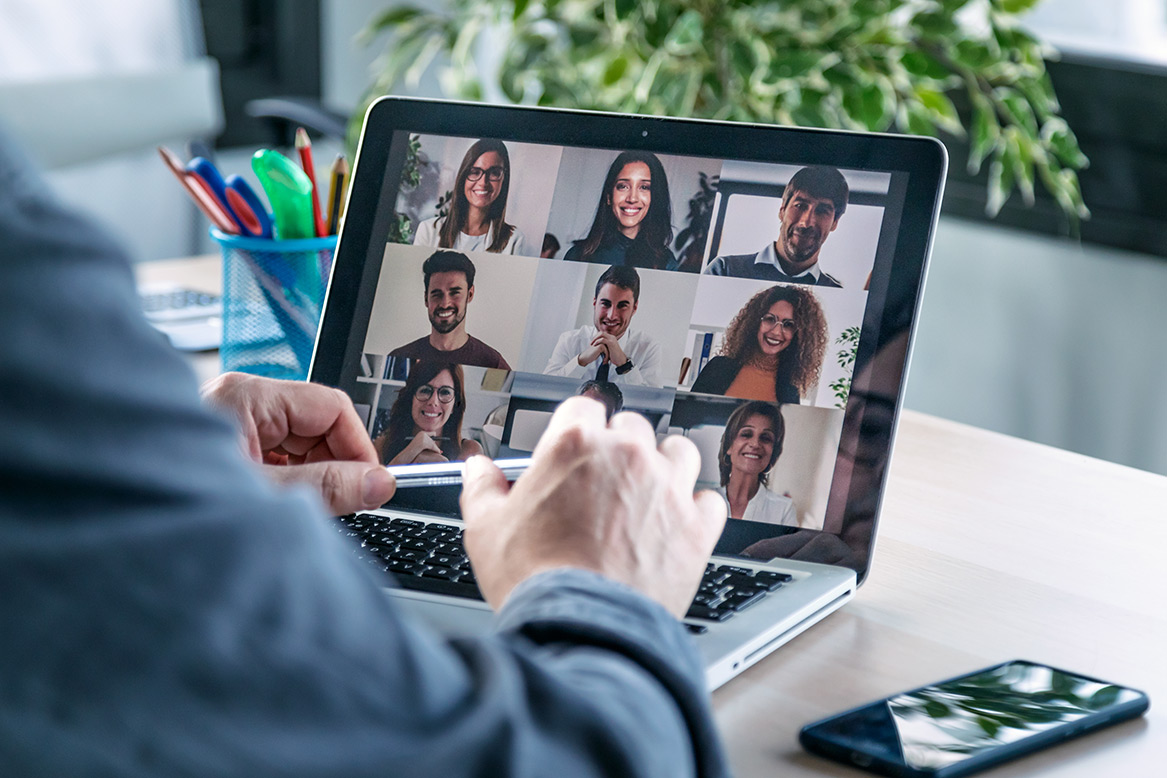 Image of a person using a laptop, screen showing multiple people on video call